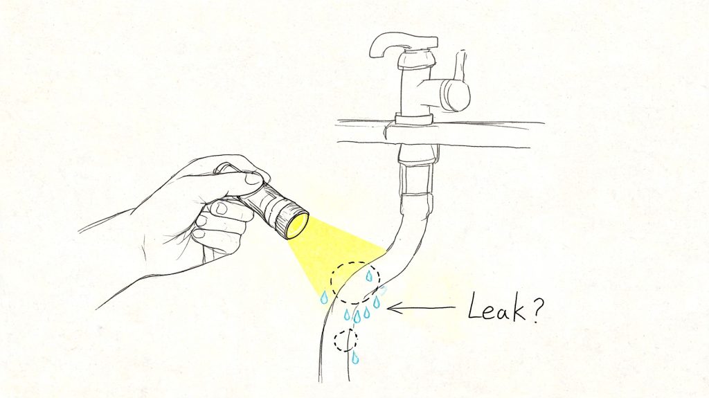 A hand holds a flashlight to inspect a potentially leaking faucet hose with water droplets shown.